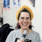 woman with microphone and yellow hat